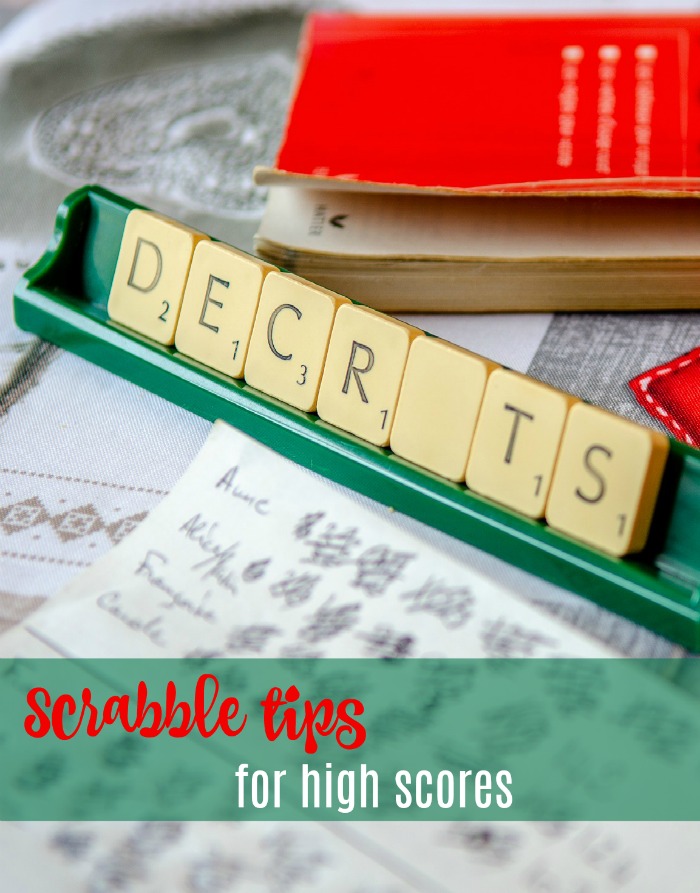 Scrabble tiles with a book and text overlay. A dictionary, piece of paper and rack of Scrabble tiles on a table with a text overlay reading "Scrabble tips for high scores".