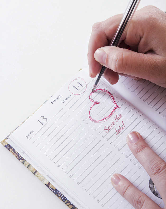 Girl drawing a heart in a calendar of February and words "Save the date."