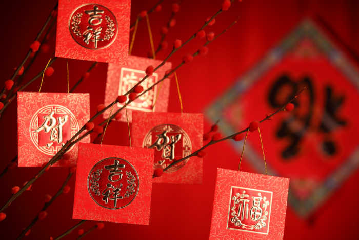 red and gold tree decorations. Red and gold square decorations hanging in branches.