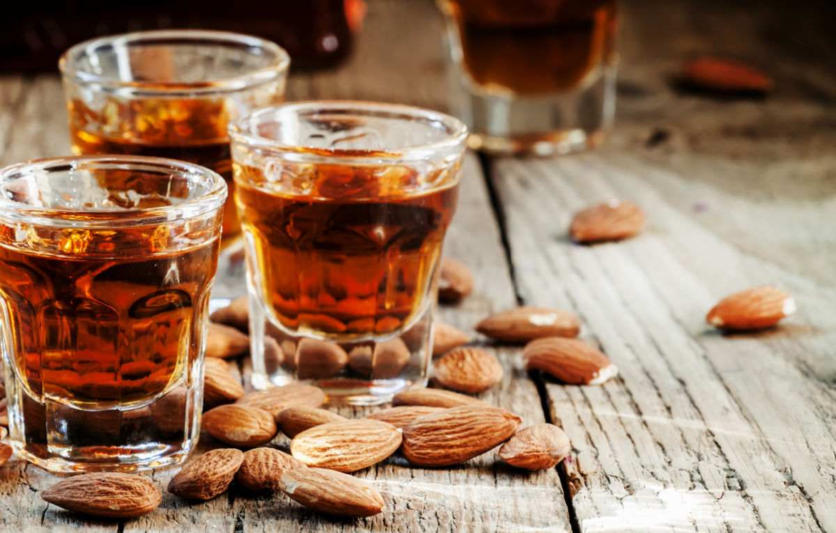 Glasses of amaretto and almonds on a wood board.
