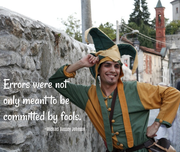 Jester leaning on a wall and text overlay about fools. Jester quote for April Fool's Day on top of a photo of a man dressed as a jester at an amusement park.