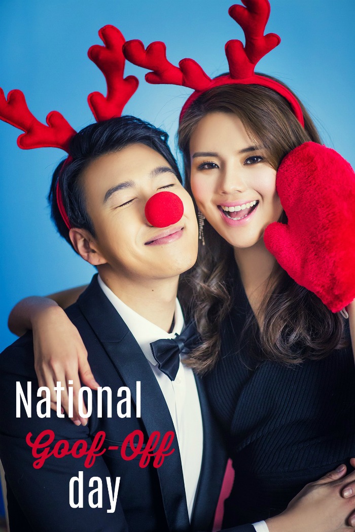 A boy and girl in red reindeer ears and a red nose. A cute couple wearing red antler headbands (the guy has on a red nose, and the woman has on a red oven mitt) with a text overlay on the photo that reads "National Goof Off Day".