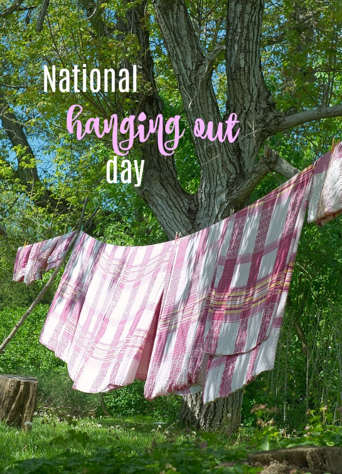 A tree with a clothesline holding red and white checked towels with a text overlay that reads "National Hanging Out Day".