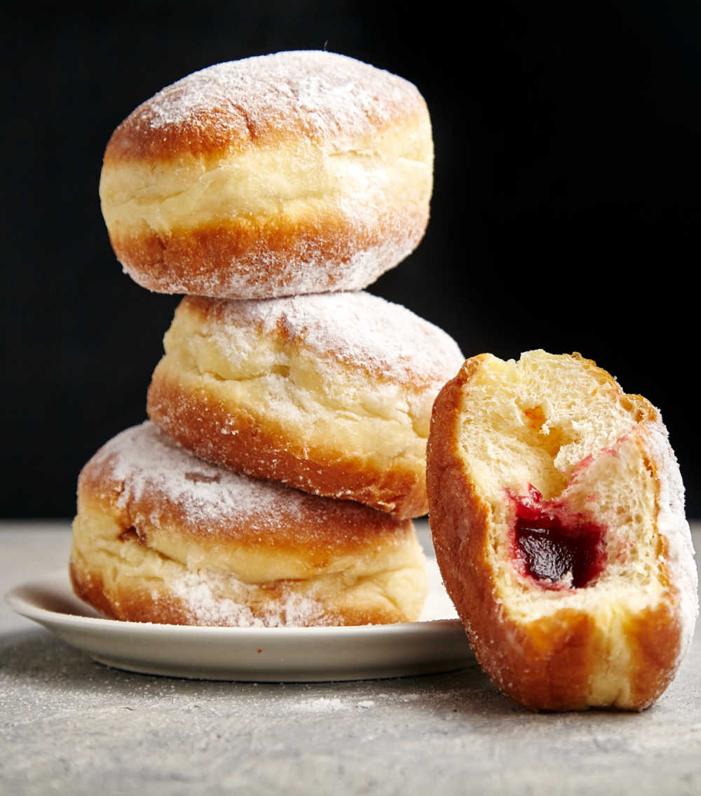 stack of jelly filled donuts on a plate.