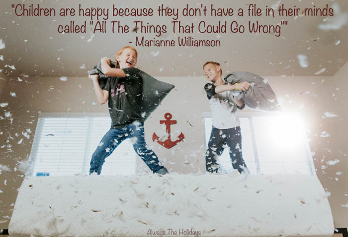 Two kids jumping on a bed having a pillow fight with a text overlay that reads "Children are happy because they don't have a file in their minds called "All The Things That Could Go Wrong"" - Marianne Williamson Children are happy because they don't have a file in their minds called "All The Things That Could Go Wrong"
