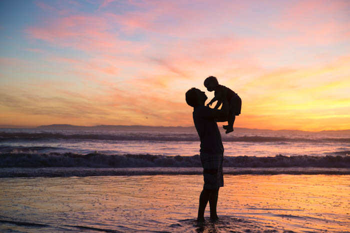father and son silhouette on the beach at sunset