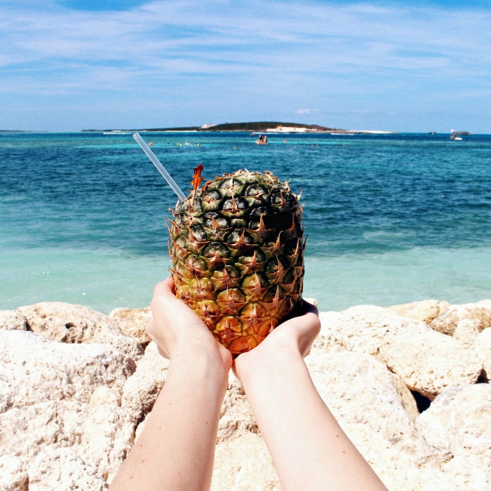Hands holding a pineapple drink for National Pina Colada Day