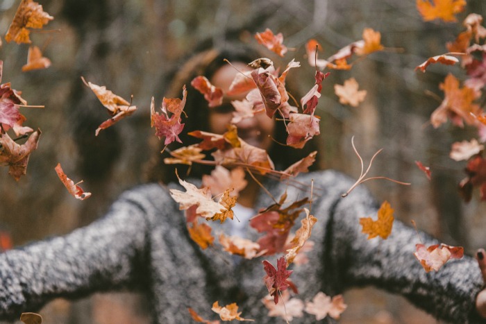 girl throwing fall leaves