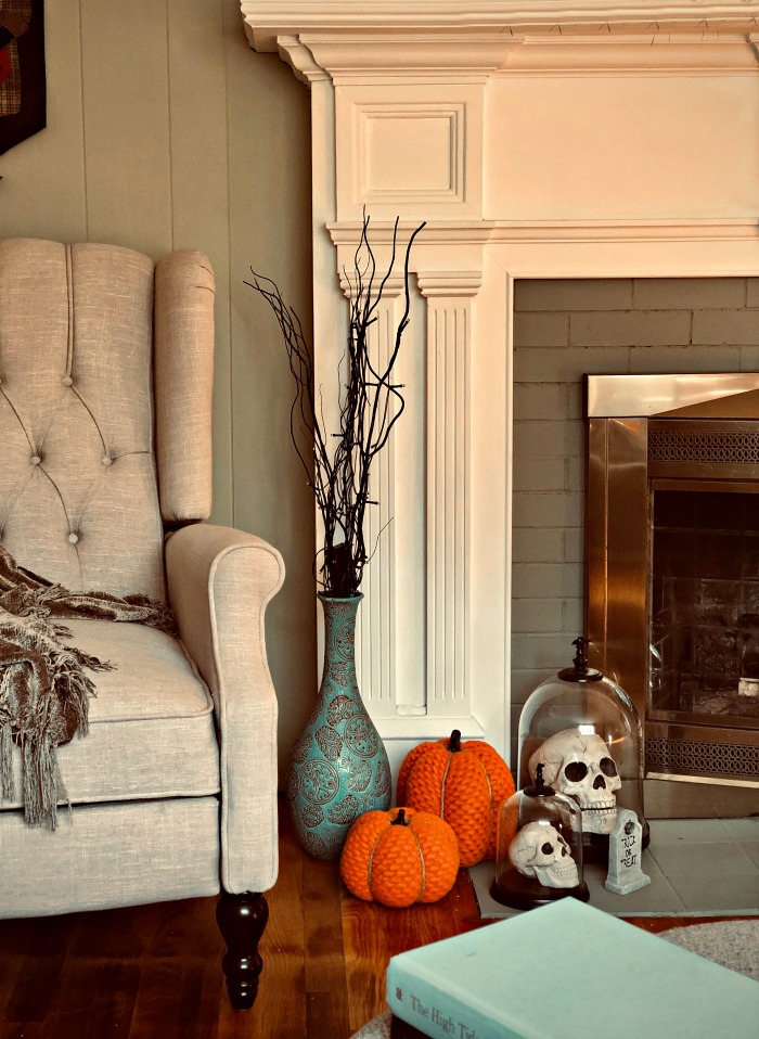fireplace scene with two plush pumpkins, a gravestone and some skulls. DIY Halloween decorations for a fireplace