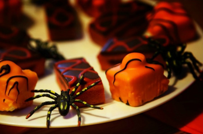 Small cakes decorated in orange frosting with plastic spiders on the plate Halloween party food