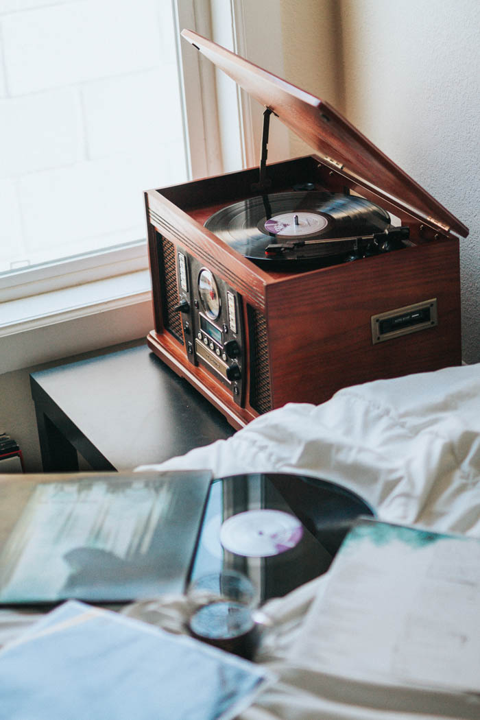 an old record player on a bedside table old record player and record on a bed. Celebrating the history of vinyl records