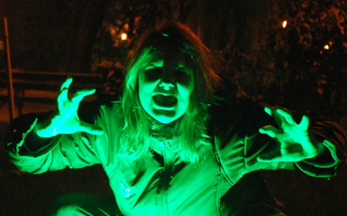 woman zombie lit up in green with a neon light woman zombie costume under a neon light