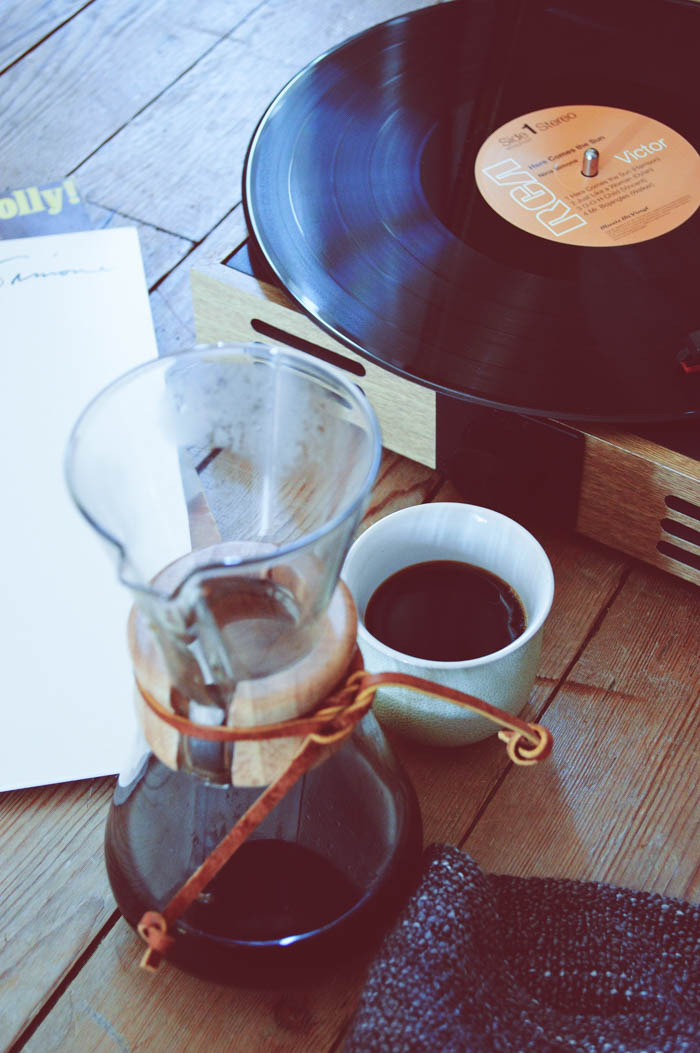 a table with a record player, record, pour over carafe, and coffee cup records and coffee
