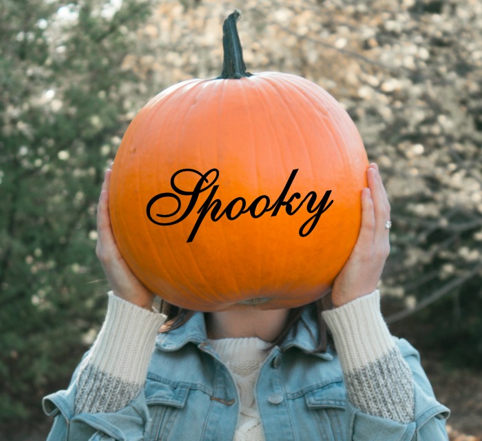 girl holding a pumpkin with the word spooky on it. Pumpkin with decals