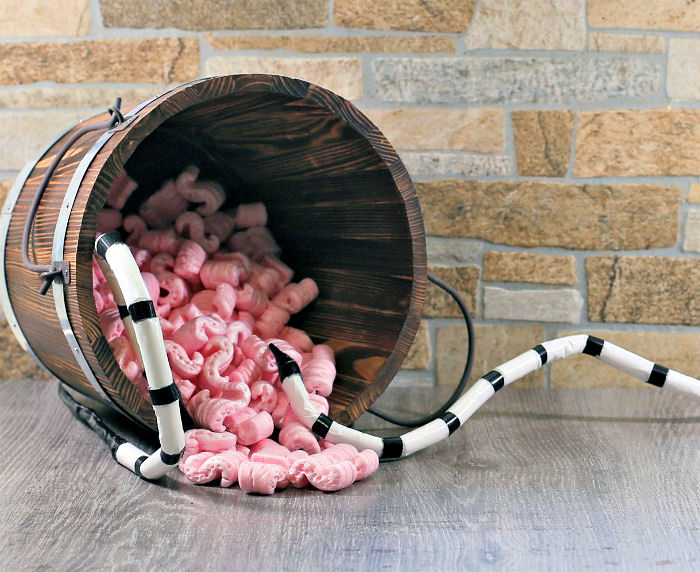 Filling a bucket with packing peanuts Bucket with packing peanuts and striped black and white snakes.