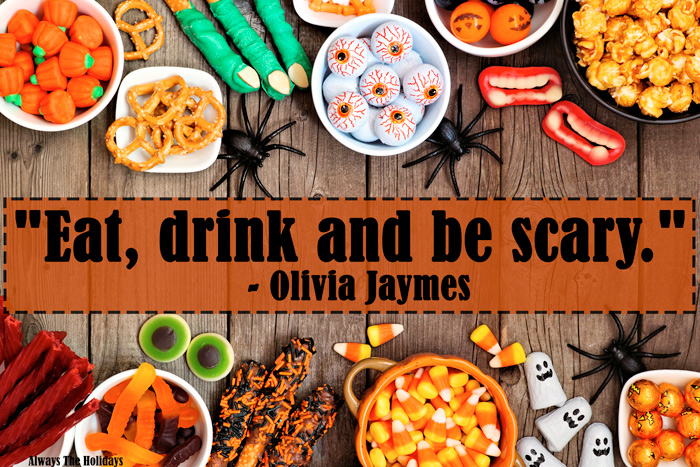 Halloween candy on a table with a funny halloween quote. A table with bowls of Halloween candy and a Halloween qoutes over it reading "Eat, drink and be scary.".