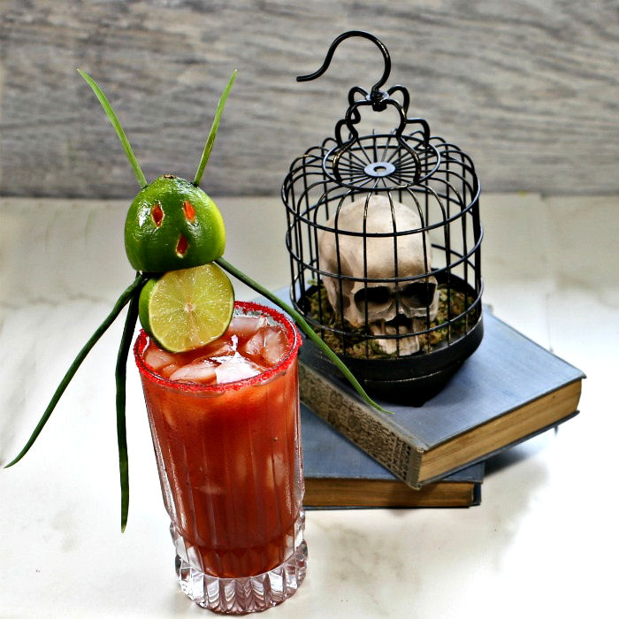 Halloween bloody Mary with a devil garnish and skull on books.