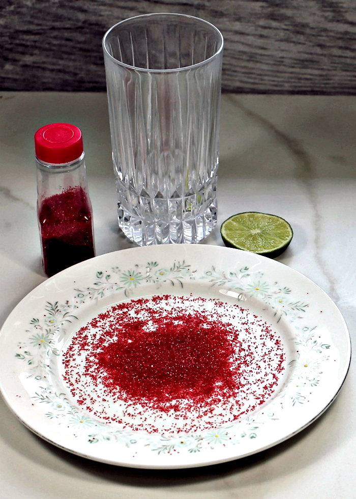 Putting red sea salt on a highball glass
