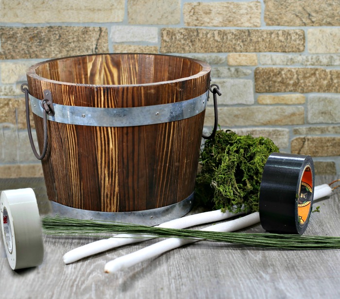 Supplies fir the Beetlejuice snake bucket project Wood bucket, moss, glue, tape, striped fabric and foam dowels.
