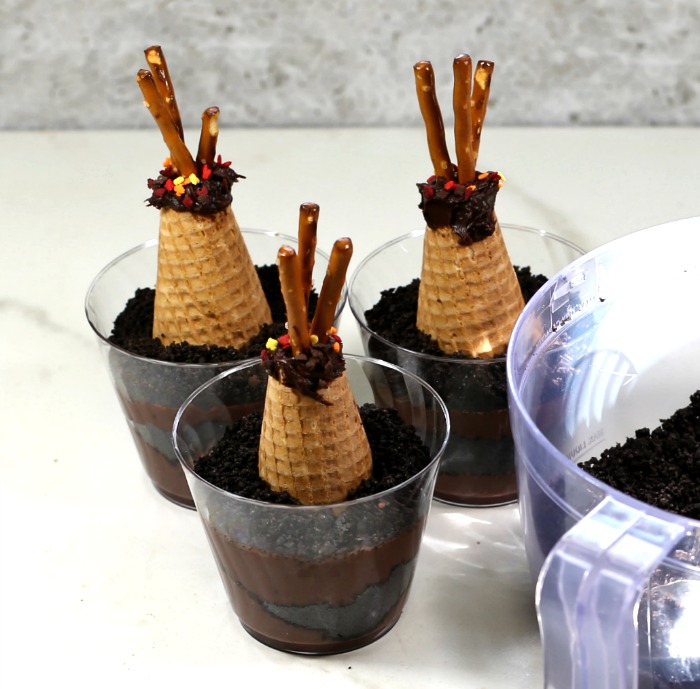 Finished teepee dirt cups. Adding Oreo crumbs to dirt cup recipe with tipis in them.