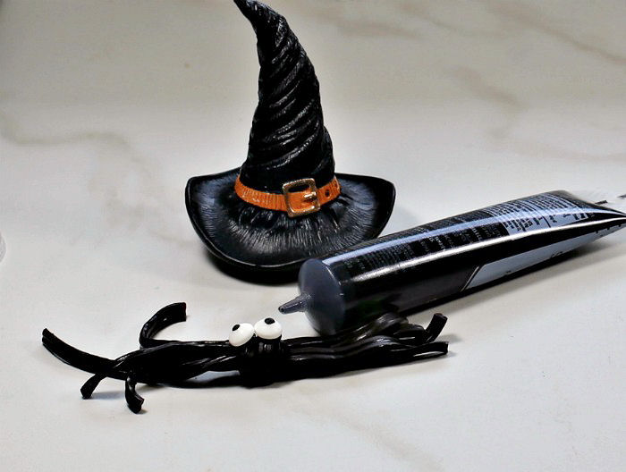 Making a licorice spider Halloween garnish A licorice spider garnish, with a tube of frosting and witch hat beside it.