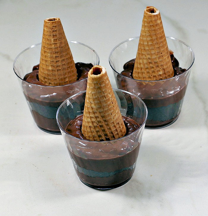 Sugar cones in pudding cups. Sugar cones in three bowls of pudding.