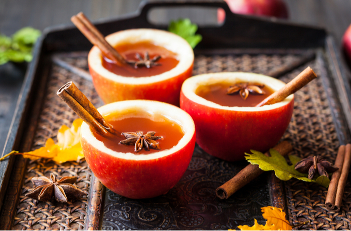 Apple cider in hollowed out oranges. Three apple cider drinks in hollowed out oranges garnished with cinnamon sticks and star anise.