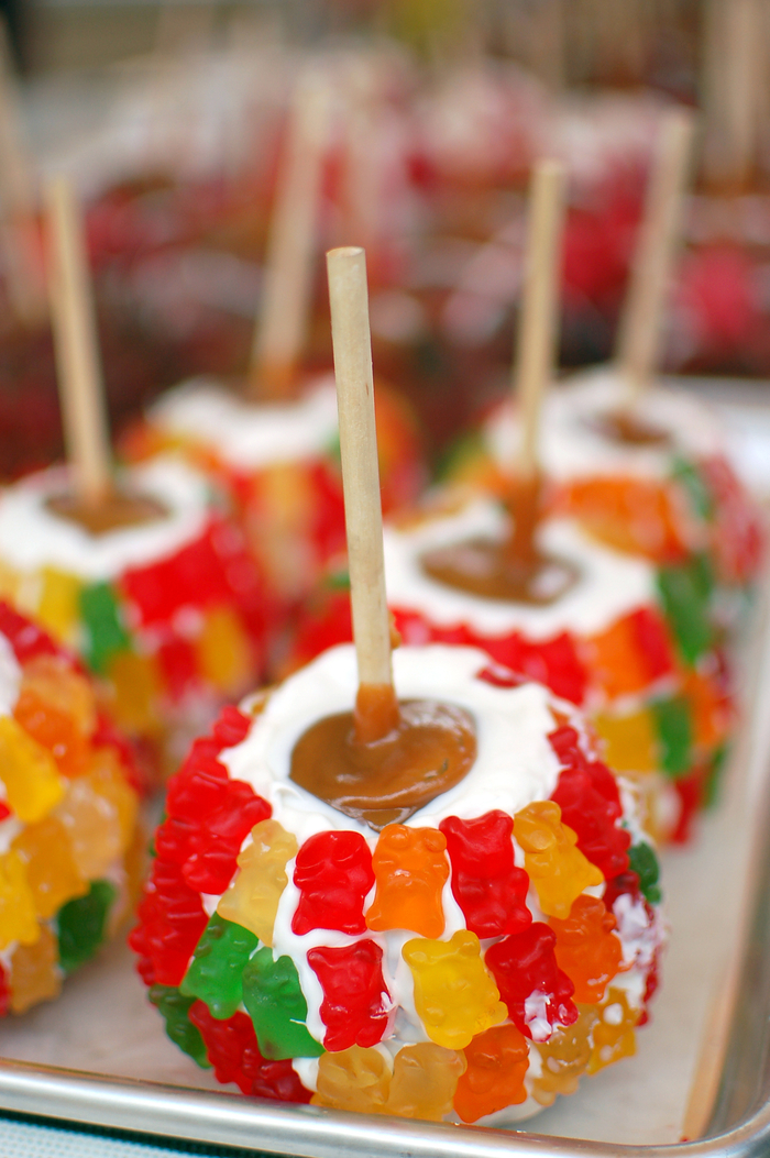 A plate of caramel apples with marshmallows and gummy bears. A plate of caramel apples with marshmallows and gummy bears.