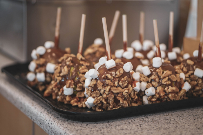A tray of caramel apples with marshmallows and walnuts. A tray of caramel apples with marshmallows and walnuts.