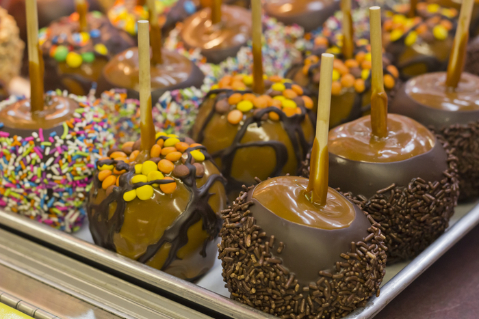 Assorted chocolate caramel apples with candy toppings. A display of assorted chocolate caramel apples with sprinkles, and other candy toppings.