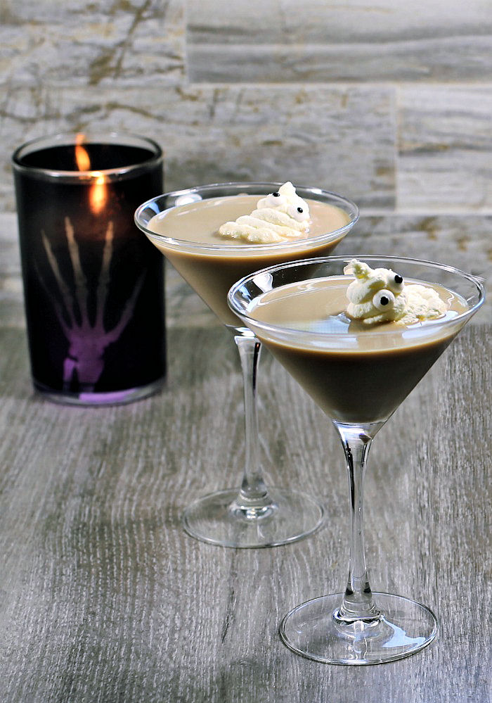 ghostbuster cocktails. Two Ghostbuster cocktails with whipped cream ghosts and a black candle.