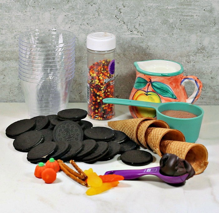 ingredients for Thanksgiving dirt cups Clear cups, sprinkles, Oreos, milk, sugar cones, pudding mix, candy and frosting.