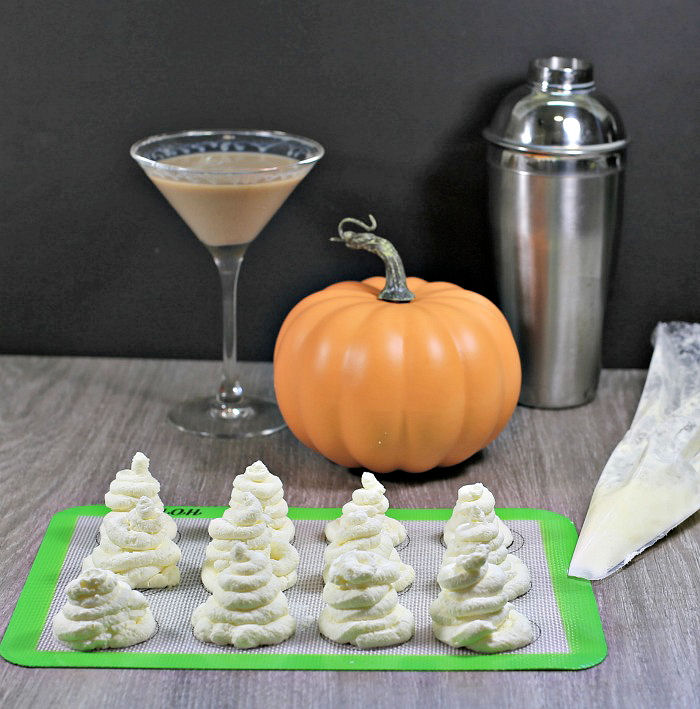 Piping whipped cream ghosts. Ghost shapes with whipped cream, pumpkin, shaker and cocktail.