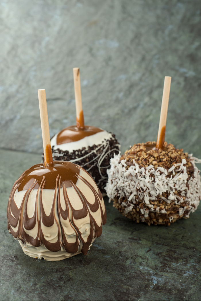 Three chocolate caramel apples with chocolate designs.