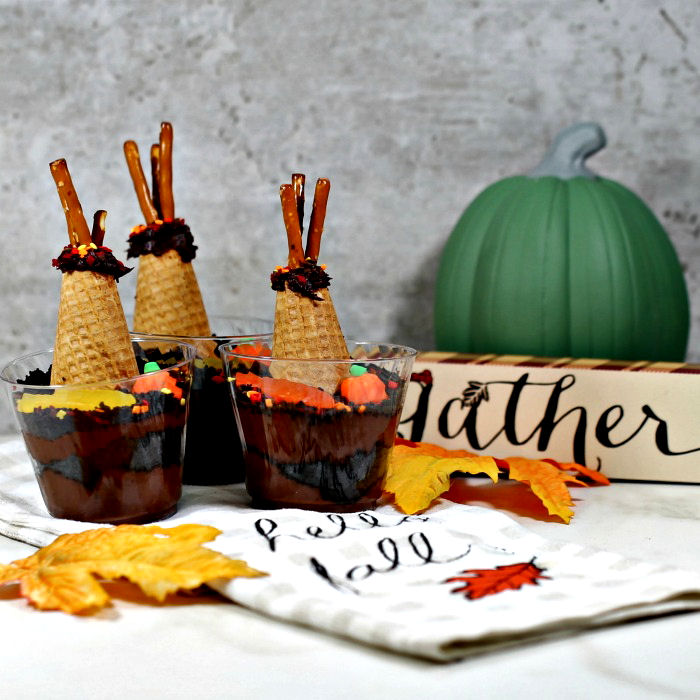 Dirt recipe chocolate pudding shaped like teepees, with sign towel, leaves and pumpkin.