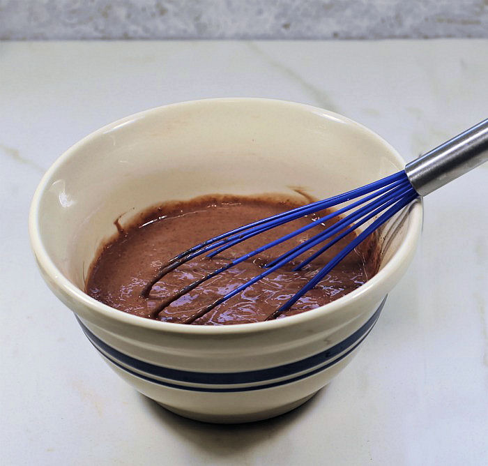 Making chocolate pudding Chocolate pudding with a blue whisk.