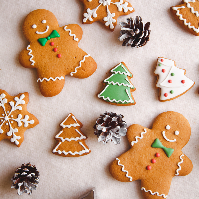 Christmas themed gingerbread cookies arranged on a flat countertop (gingerbread men, Christmas trees and snowflakes).