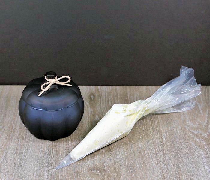 whipped cream in piping bag Whipped cream in a piping bag with a black pumpkin candle.