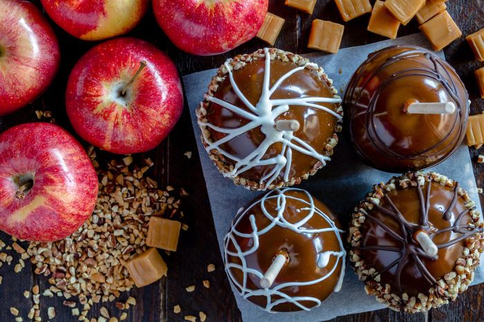 Two white chocolate caramel apples and two dark chocolate caramel apples on a plate. Two white chocolate caramel apples and two dark chocolate caramel apples on a plate.