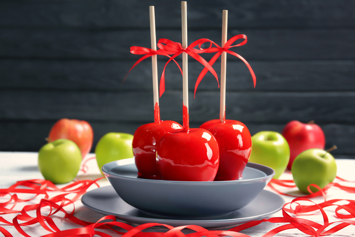 Three candy apples with bows on them, on a plate. Three candy apples with bows on them, on a plate paying homage to the man who invented the caramel apple.