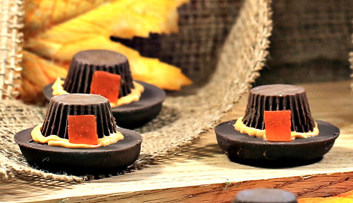 Pilgrim hat cookies Three pilgrim hat dessert cookies on a wooden board with burlap and leaves.