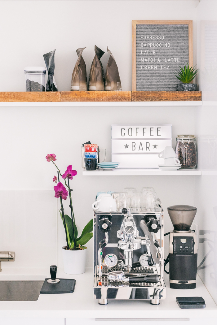 A decorated coffee bar. A coffee bar with an espresso machine, coffee, a "coffee bar" sign and decor.
