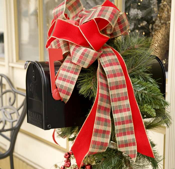 Decorated mailbox for Christmas Black mailbox with red plaid ribbon and garland on top.