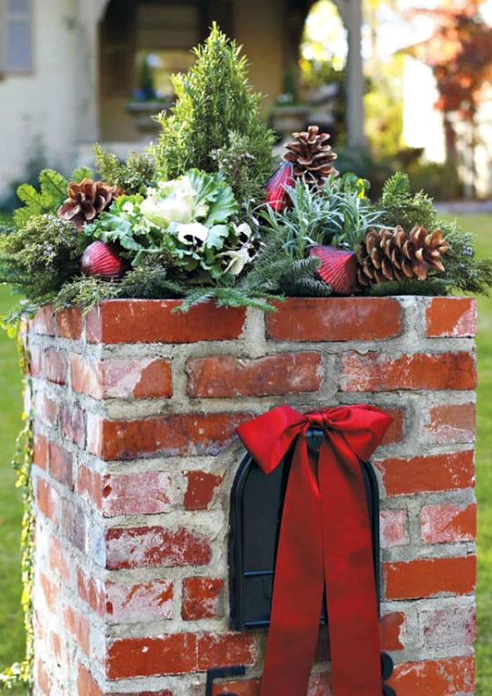 Brick mail box with greenery on top and red bow.