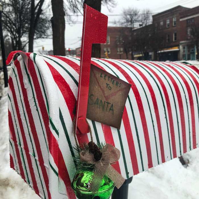 Mailbox decorated with candy cane paper. Red and white striped mailbox with bells and letter to Santa sign.
