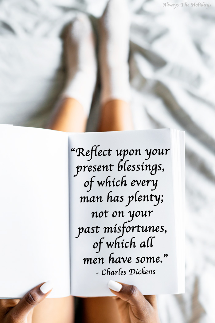 A person sitting on a bed holding a journal with a Charles Dickens quote for Thanksgiving.