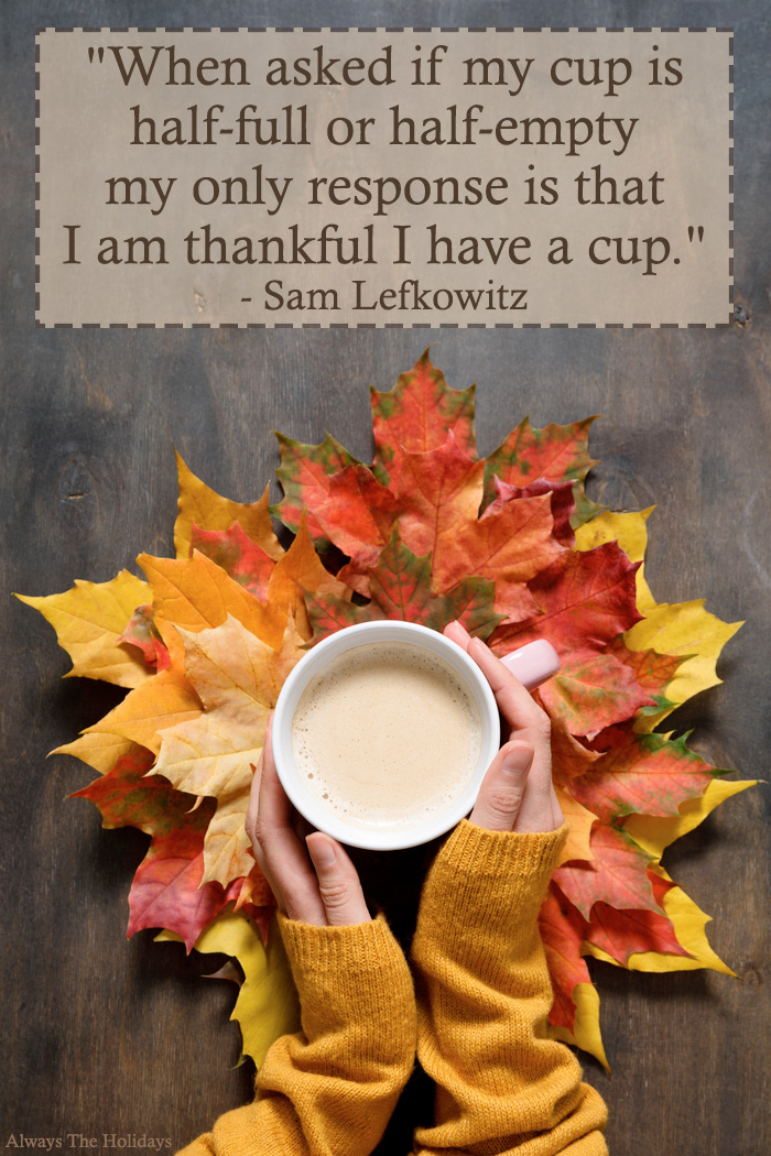 A woman's hands holding a latte over leaves with a Thanksgiving quote text overlay reading "When asked if my cup is half-full or half-empty my only response is that I am thankful I have a cup.".