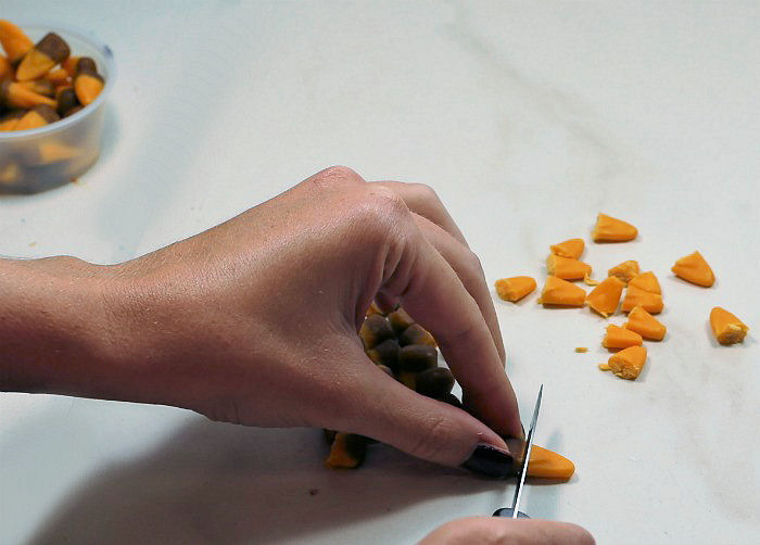 Cutting candy corn female hand cutting pieces of Harvest Corn.