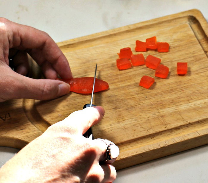 cutting Swedish fish into cubes. Female hands cutting Swedish fish into squares on a cutting board.
