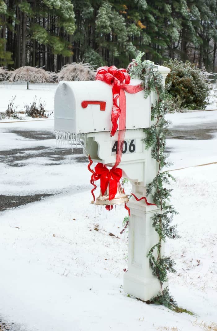 Red decorations and garland on a white mailbox.